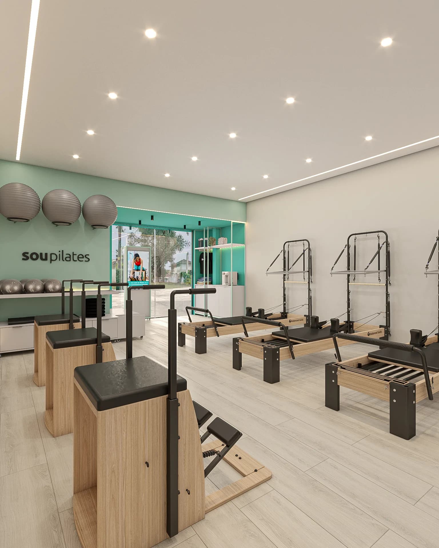Recepção da Sou Pilates com bolas suíças, letreiro da marca e vista para a rua.