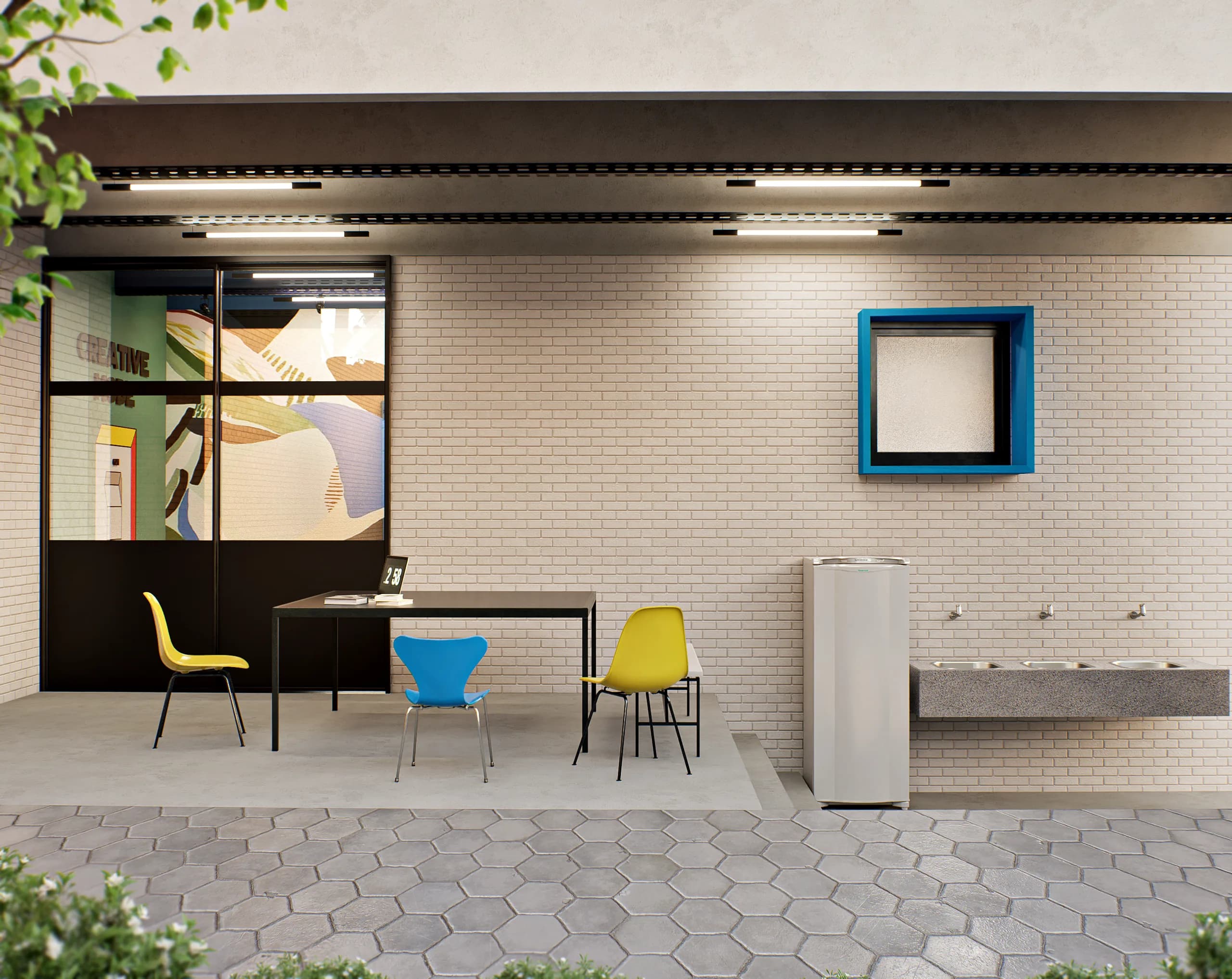 Área externa do Diretório Acadêmico com piso de pedra, mesa com cadeiras amarelas e azul e bancada de inox junto à parede de tijolinhos.