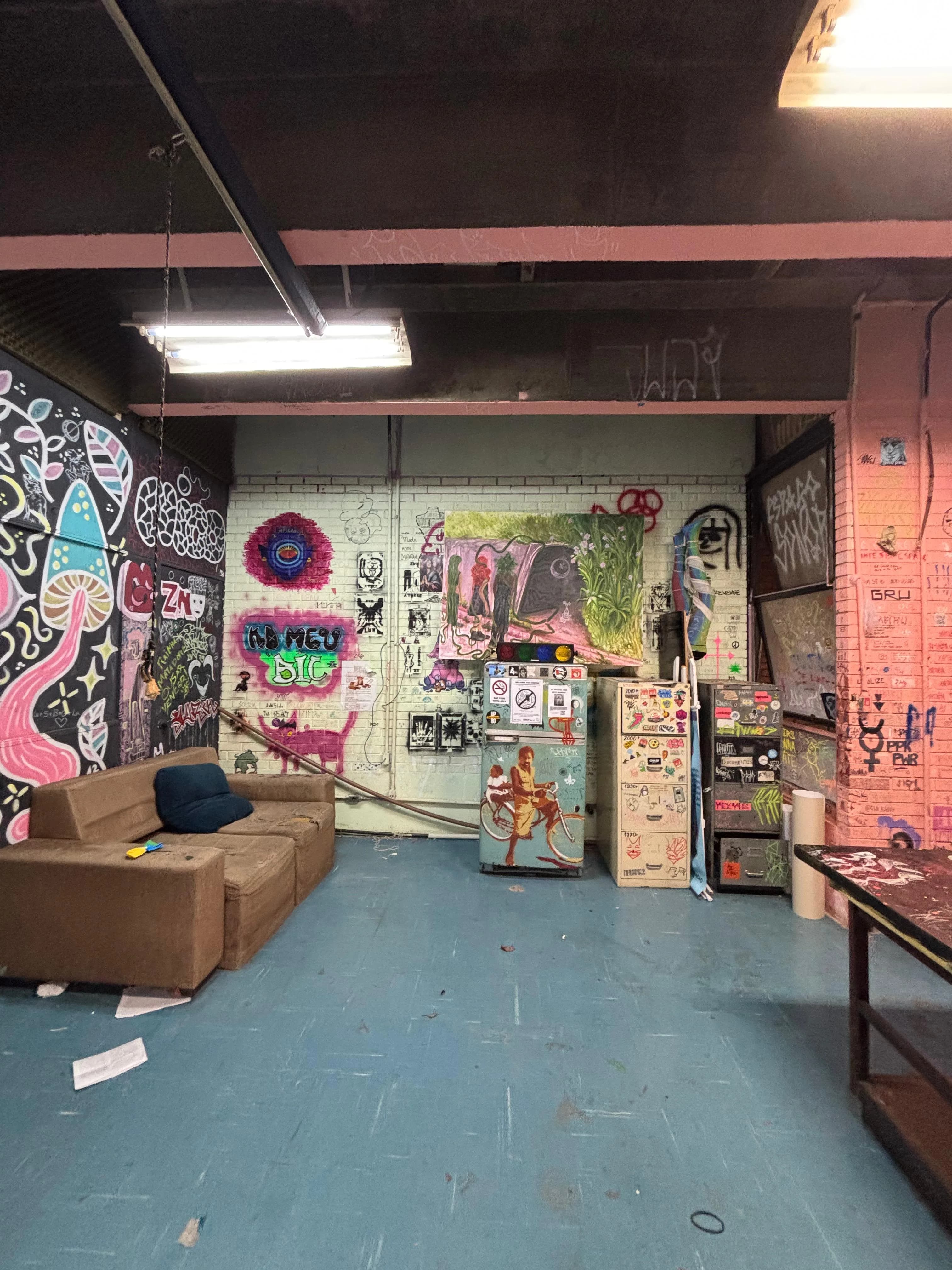 Antes da reforma: sala do Diretório Acadêmico com sofá marrom, grafites nas paredes e piso azul.