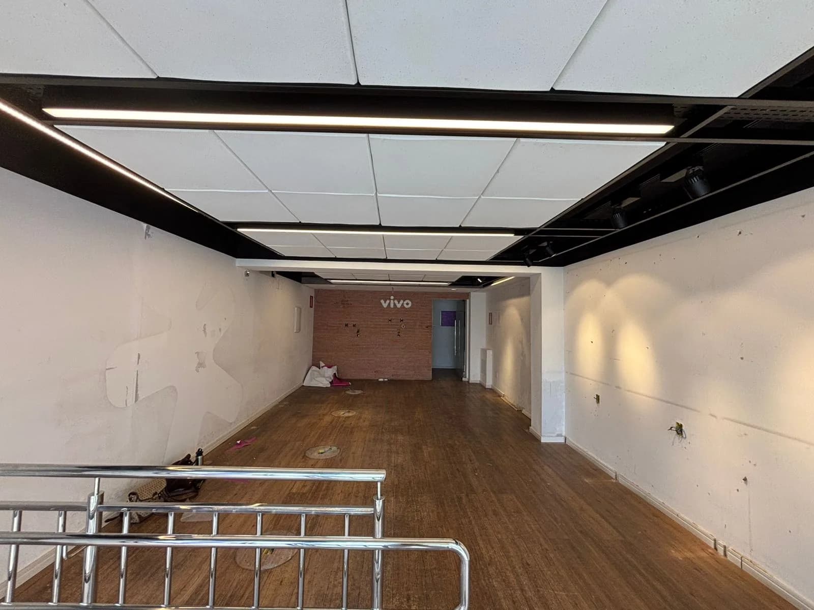 Antes da Gigi Bambini: o salão visto da entrada, com o guarda-corpo em primeiro plano e a parede de tijolos ao fundo.