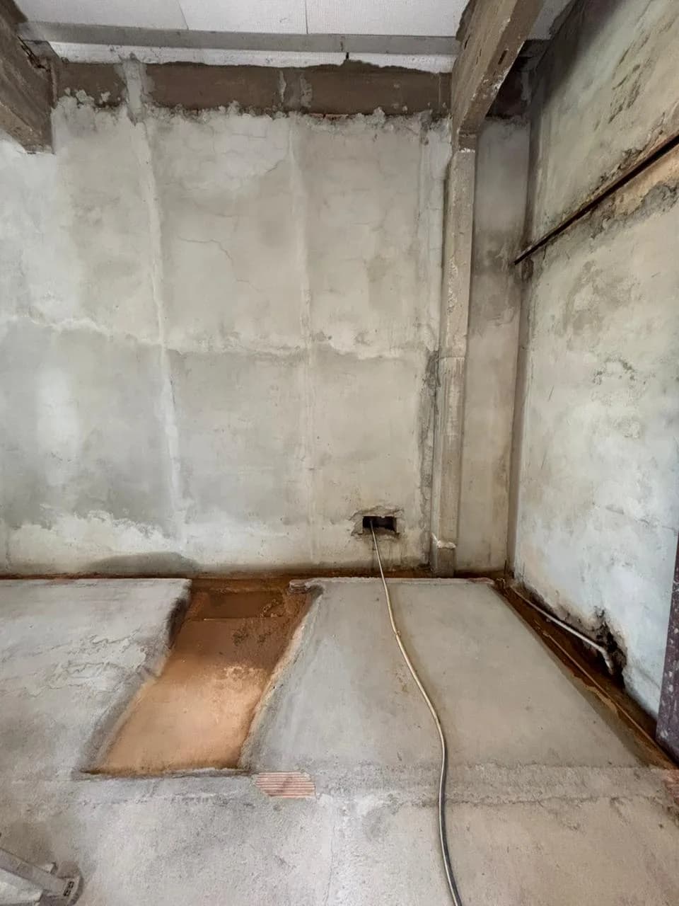 Antes da obra da Sou Pilates: parede sem reboco e contrapiso com uma canaleta aberta.