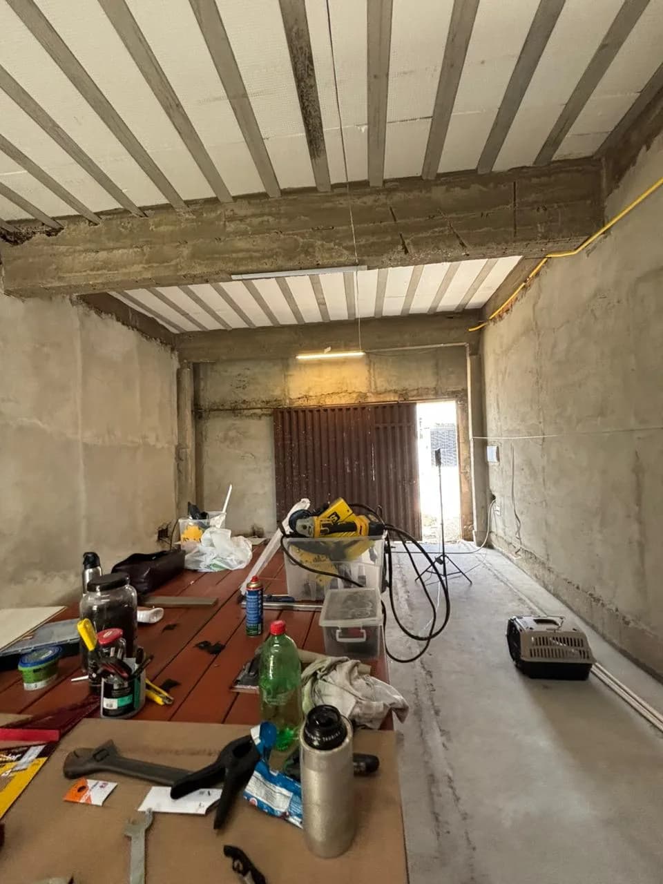 Antes da obra da Sou Pilates: salão com laje de vigotas aparente e ferramentas espalhadas pelo chão.