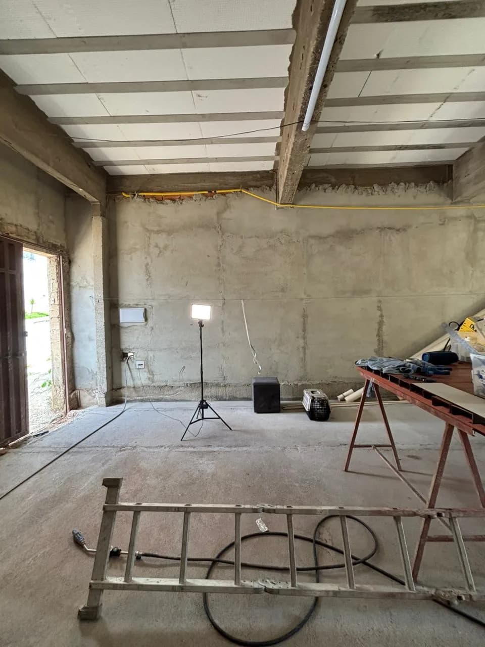 Antes da obra da Sou Pilates: salão em obra com escada deitada no chão, refletor e bancada de trabalho.