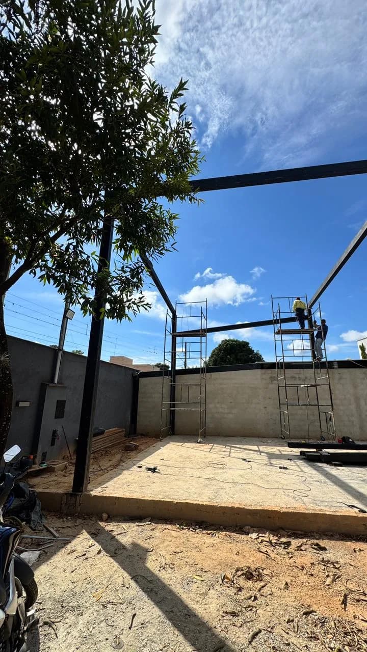 Antes da Altimetria: terreno em obra bruta com a estrutura metálica do telhado sendo montada, sob céu azul.