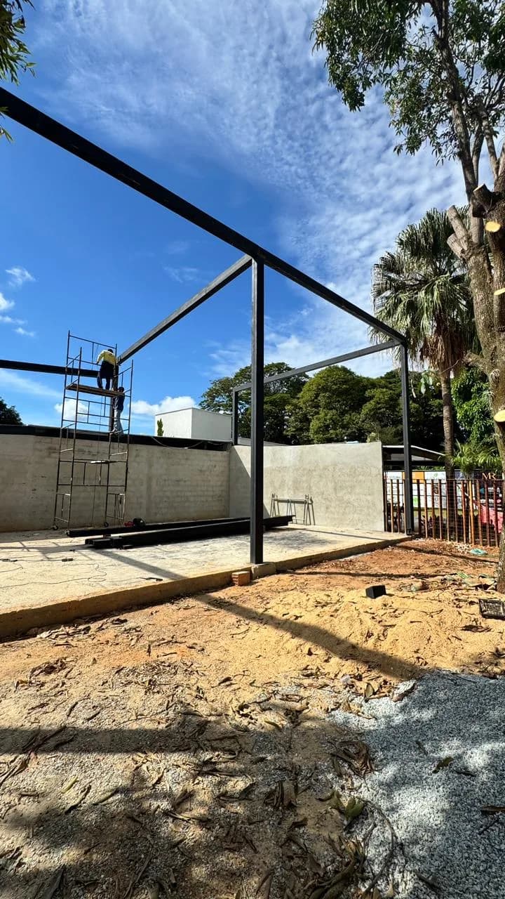 Antes da Altimetria: estrutura metálica e muro de blocos no terreno em obra, com andaime ao fundo.