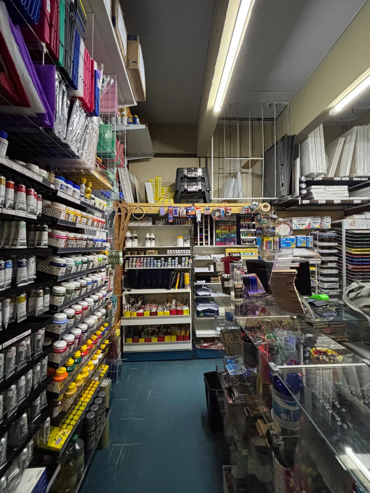 Interior de uma papelaria com prateleiras lotadas de produtos do chão ao teto.